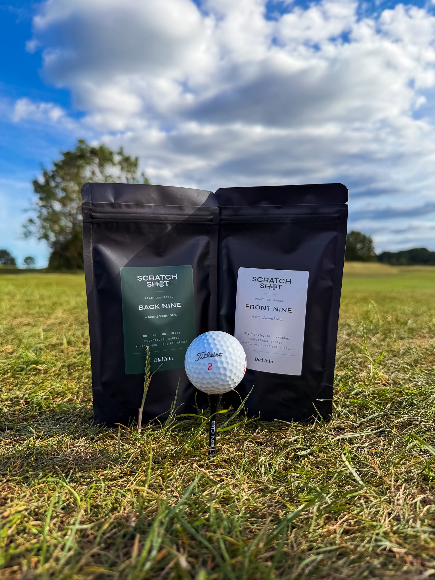 two bags of scratch shot coffee  behind a golf ball